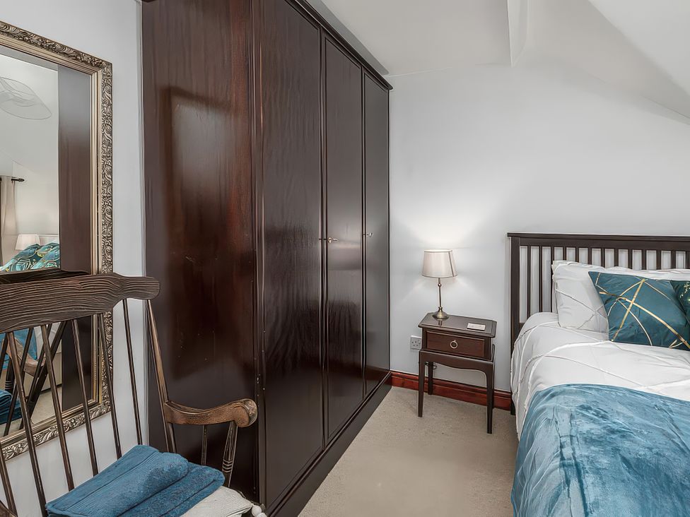 A bedroom with a wardrobe, bed, table and lamp at Preswylfa