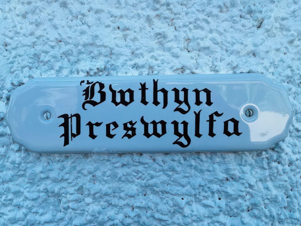 A nameplate with 'Bwthyn Preswylfa' mounted on a textured wall