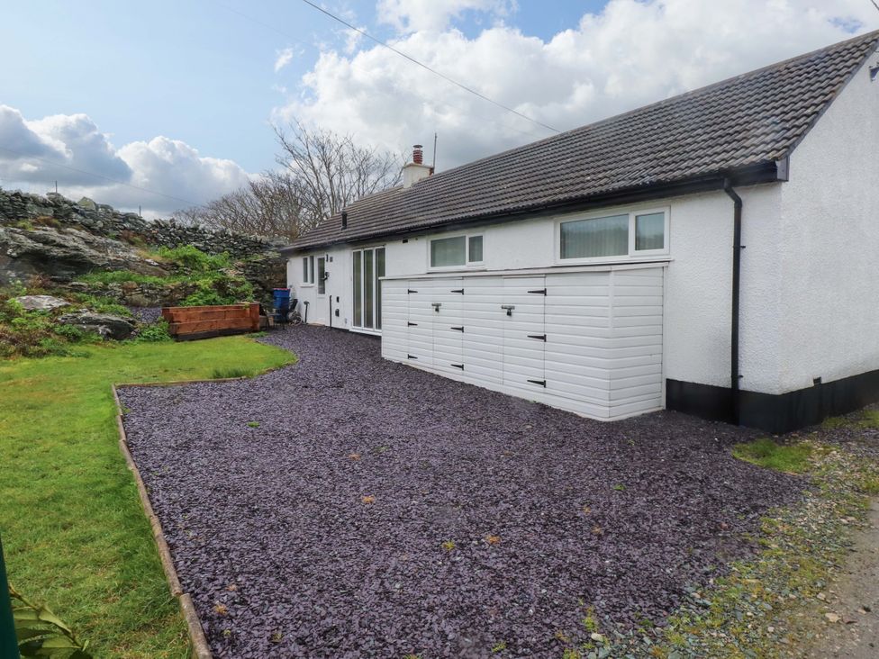 A house with a gravel garden and wooden bench at Y Byngalo in Trearddur Bay