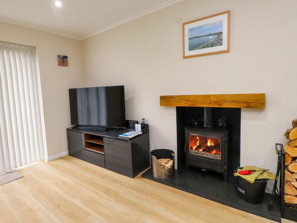 A living room with a television and fireplace at Y Byngalo in Trearddur Bay
