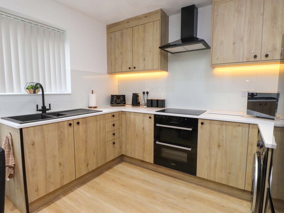 A kitchen with cabinets and appliances at Y Byngalo in Trearddur Bay