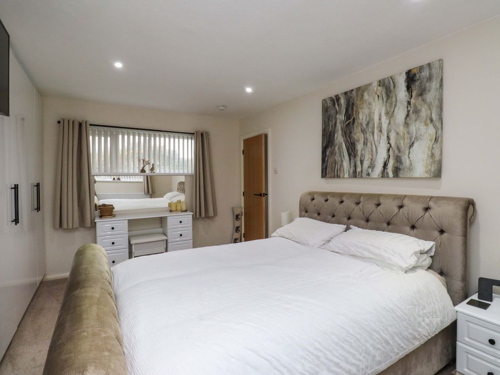 A bedroom with a bed and dressing table at Y Byngalo in Trearddur Bay