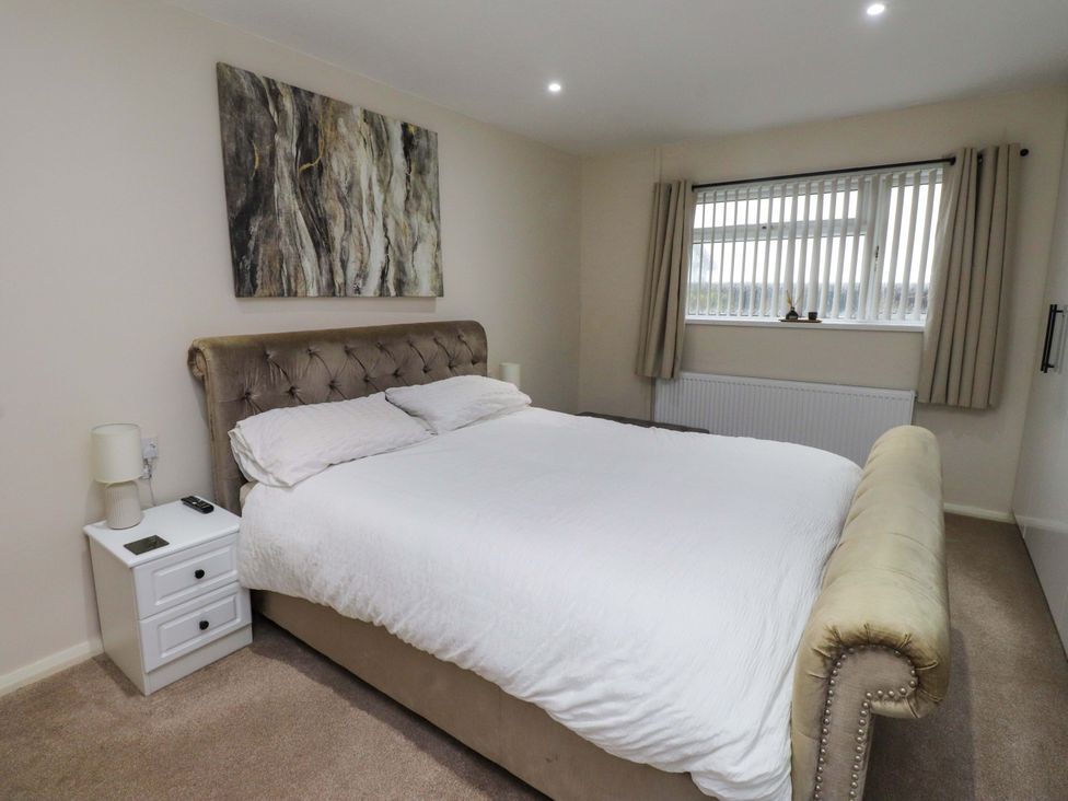 A bedroom with a bed and nightstand at Y Byngalo Trearddur Bay