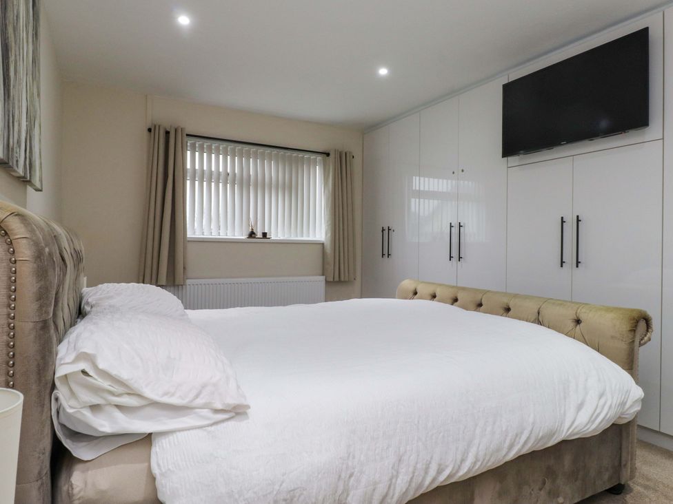 A bedroom with a bed and wardrobe at Y Byngalo Trearddur Bay