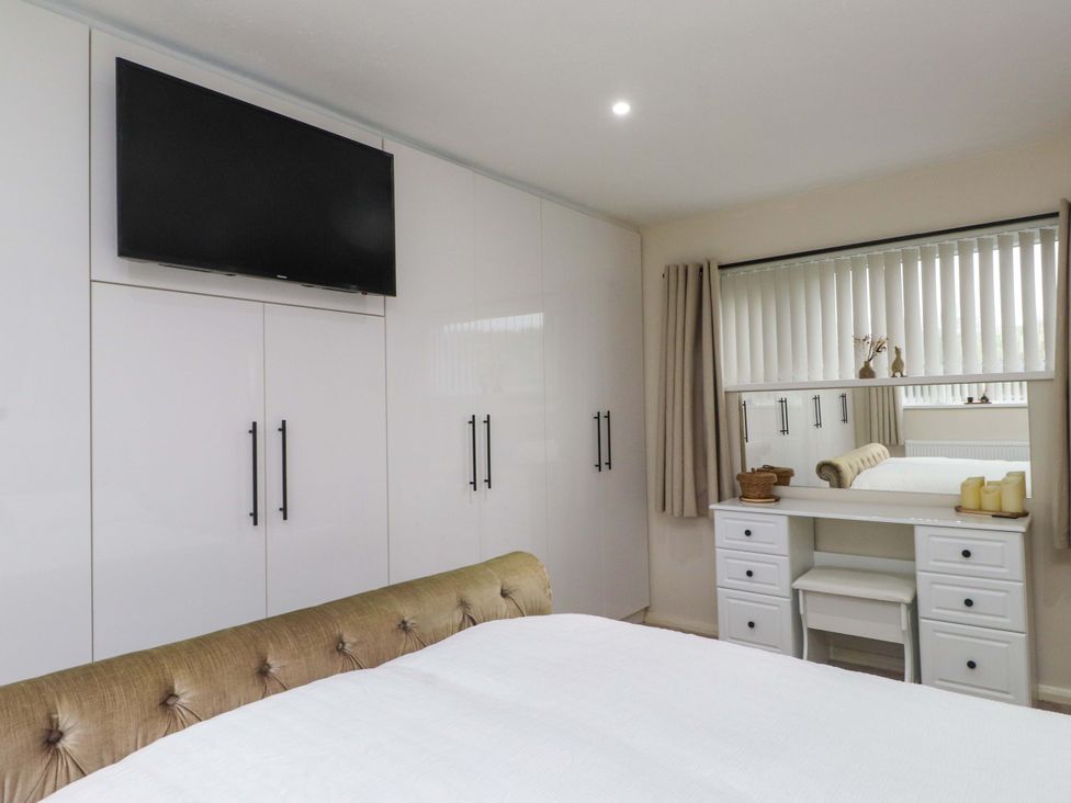 A bedroom with a television and a dressing table at Y Byngalo in Trearddur Bay