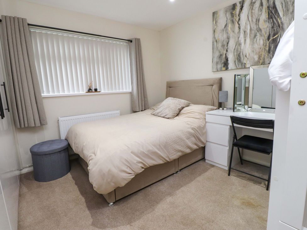 A bedroom with a bed and dressing table at Y Byngalo Trearddur Bay