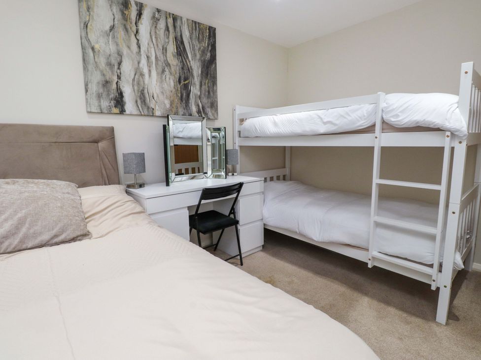 A bedroom with a bunk bed and a desk at Y Byngalo in Trearddur Bay