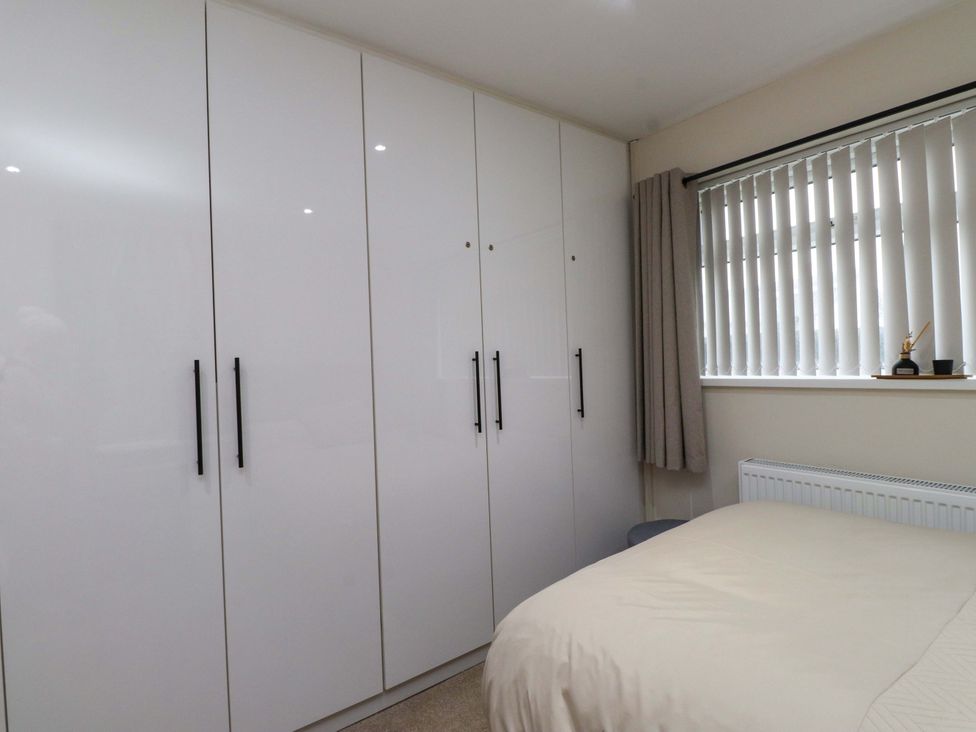 A bedroom with a wardrobe and bed at Y Byngalo Trearddur Bay