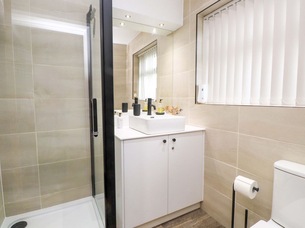 A bathroom with a shower, sink and toilet at Y Byngalo Trearddur Bay