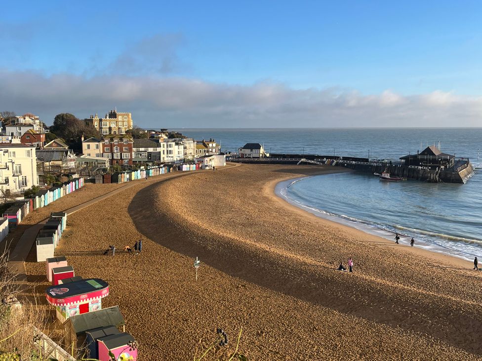 A beach with pier and colorful beach huts at Broadstairs Beach in Broadstairs