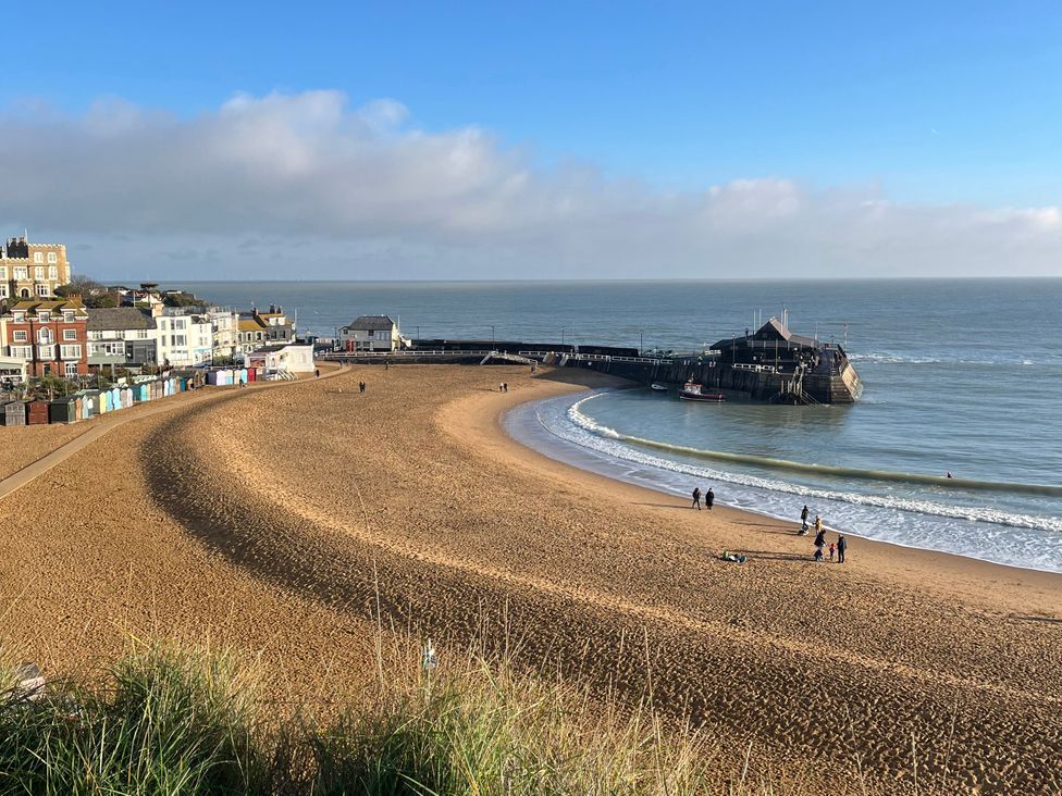 A beach view with a pier and people at Broadstairs Beach in Broadstairs