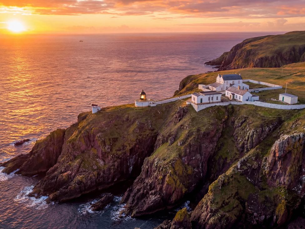 A lighthouse on a cliff with buildings overlooking the sea at The Lighthouse Keepers Cottage St Abbs