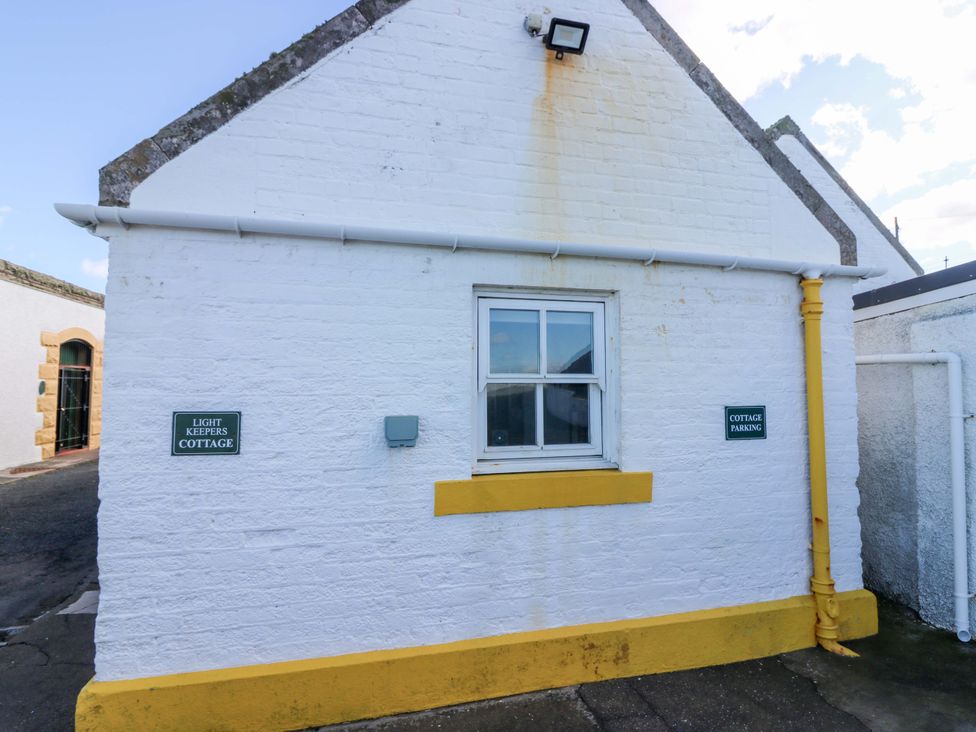 An outdoor view of Light Keepers Cottage with a parking sign at The Lighthouse Keepers Cottage St Abbs