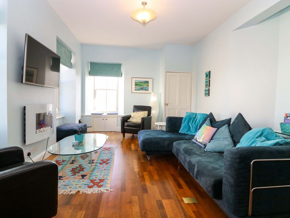 A living room with a sofa, coffee table, and television at The Lighthouse Keepers Cottage, St Abbs