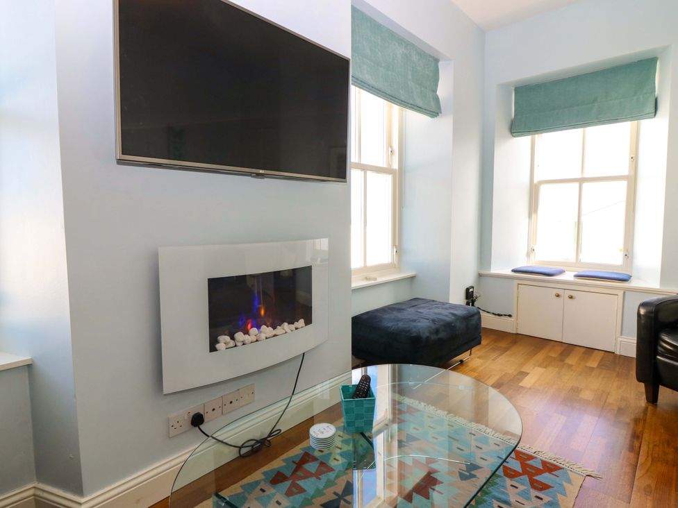 A living room with a television and an electric fireplace at The Lighthouse Keepers Cottage St Abbs