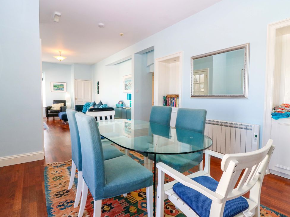 A dining room with a glass table and blue chairs at The Lighthouse Keepers Cottage St Abbs