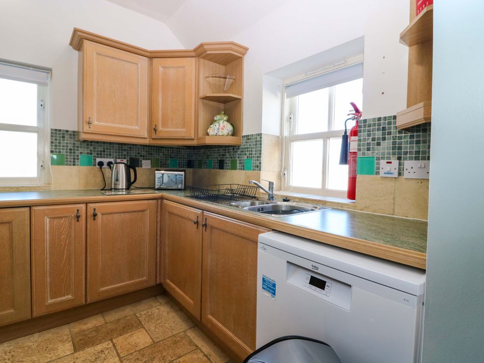 A kitchen with cabinets, sink, dishwasher, and appliances at The Lighthouse Keepers Cottage St Abbs
