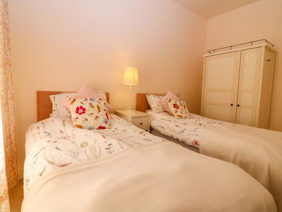 A bedroom with two beds and a wardrobe at The Lighthouse Keepers Cottage in St Abbs