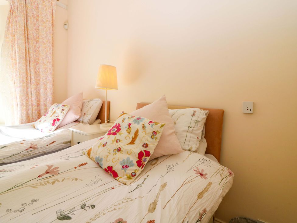 A bedroom with twin beds and a lamp at The Lighthouse Keepers Cottage in St Abbs