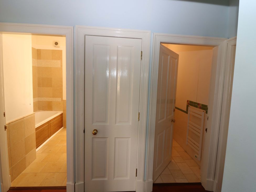 A hallway with three doors leading to a bathroom at The Lighthouse Keepers Cottage St Abbs