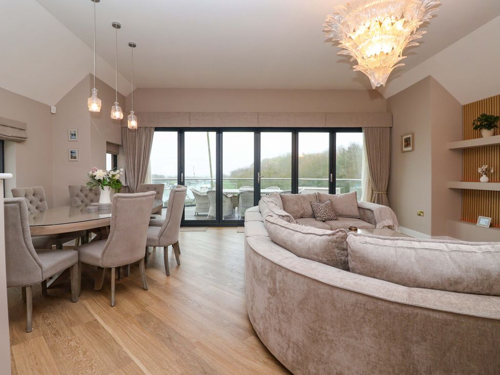 A living room with a dining area and glass doors at Swing Bridge Cottage