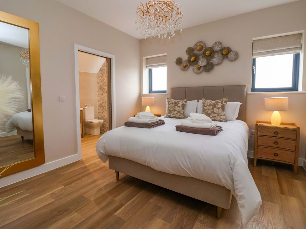 A bedroom with a bed, dresser and mirror at Swing Bridge Cottage 