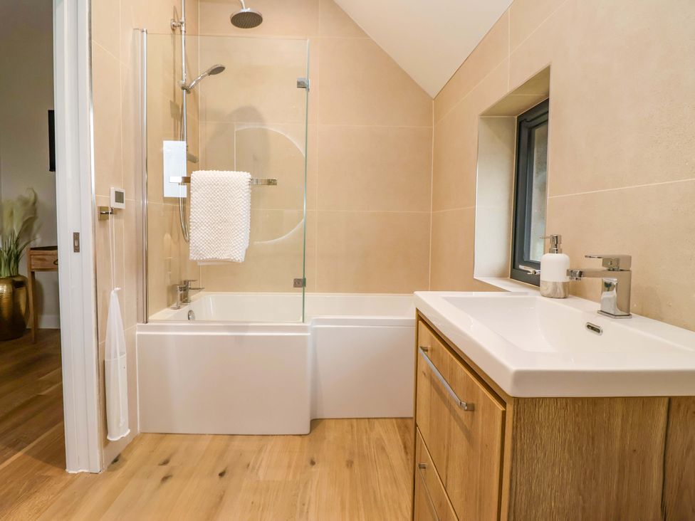 A bathroom with a bathtub and sink at Swing Bridge Cottage
