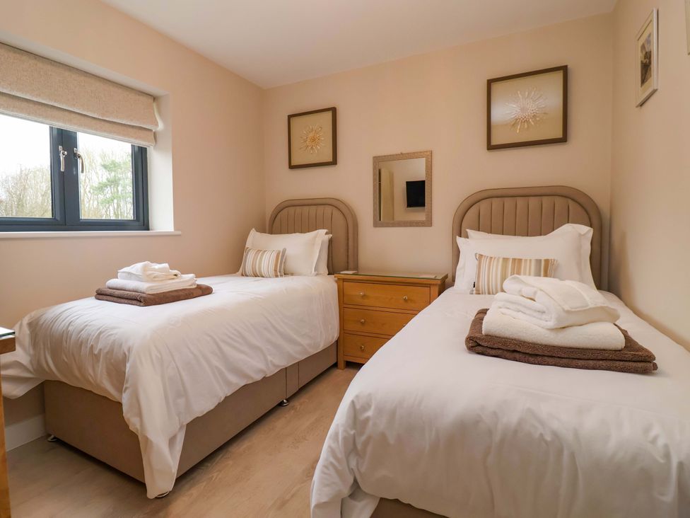 A bedroom with two beds and a bedside table at Swing Bridge Cottage
