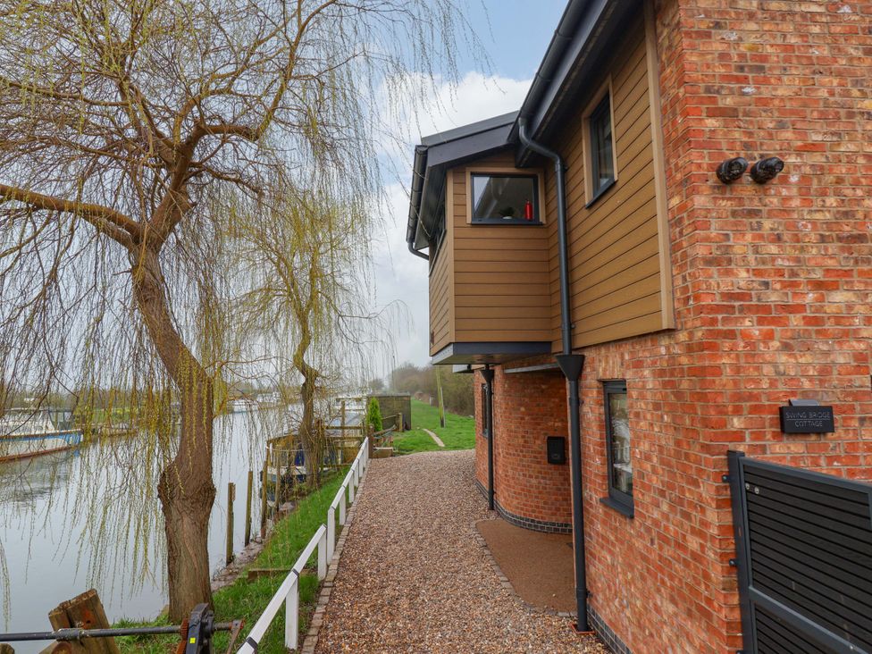 An exterior view of a cottage near a river at Swing Bridge Cottage