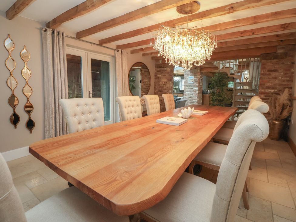 A dining room with a wooden table and chandelier at Mill Race Cottage in Driffield