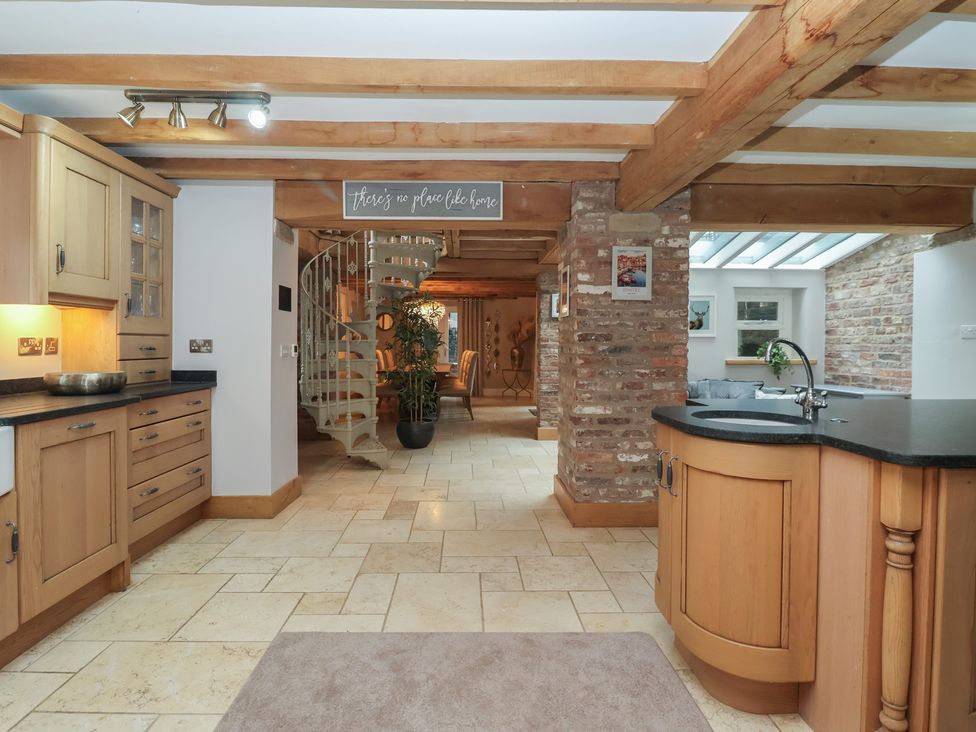 A kitchen with a spiral staircase and wooden cabinets at Mill Race Cottage in Driffield