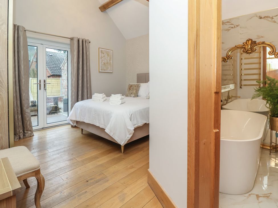 A bedroom with a bed and a view of a bathroom at Mill Race Cottage in Driffield