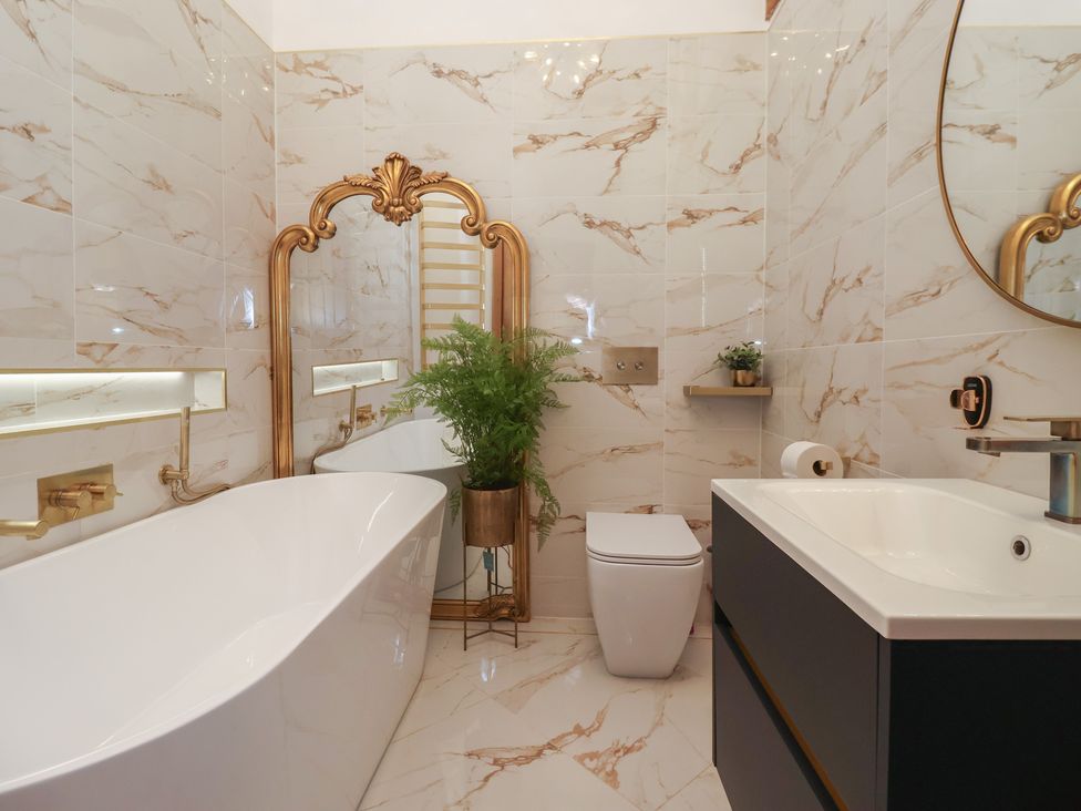 A bathroom with a bathtub, sink, and toilet at Mill Race Cottage in Driffield