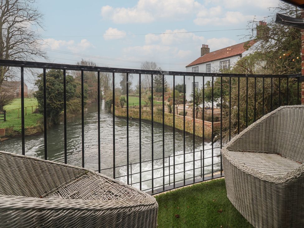 An outdoor space with river view and chairs at Mill Race Cottage in Driffield