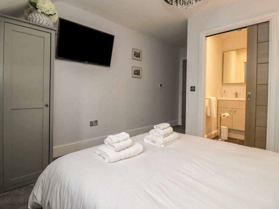 A bedroom with a bed and a bathroom entrance at Mill Race Cottage in Driffield