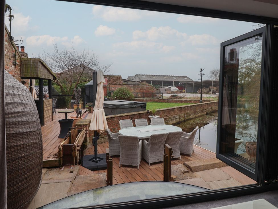 An outdoor deck area with a table and chairs at Mill Race Cottage in Driffield