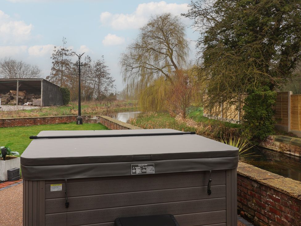 A garden with a hot tub and a view of water at Mill Race Cottage in Driffield