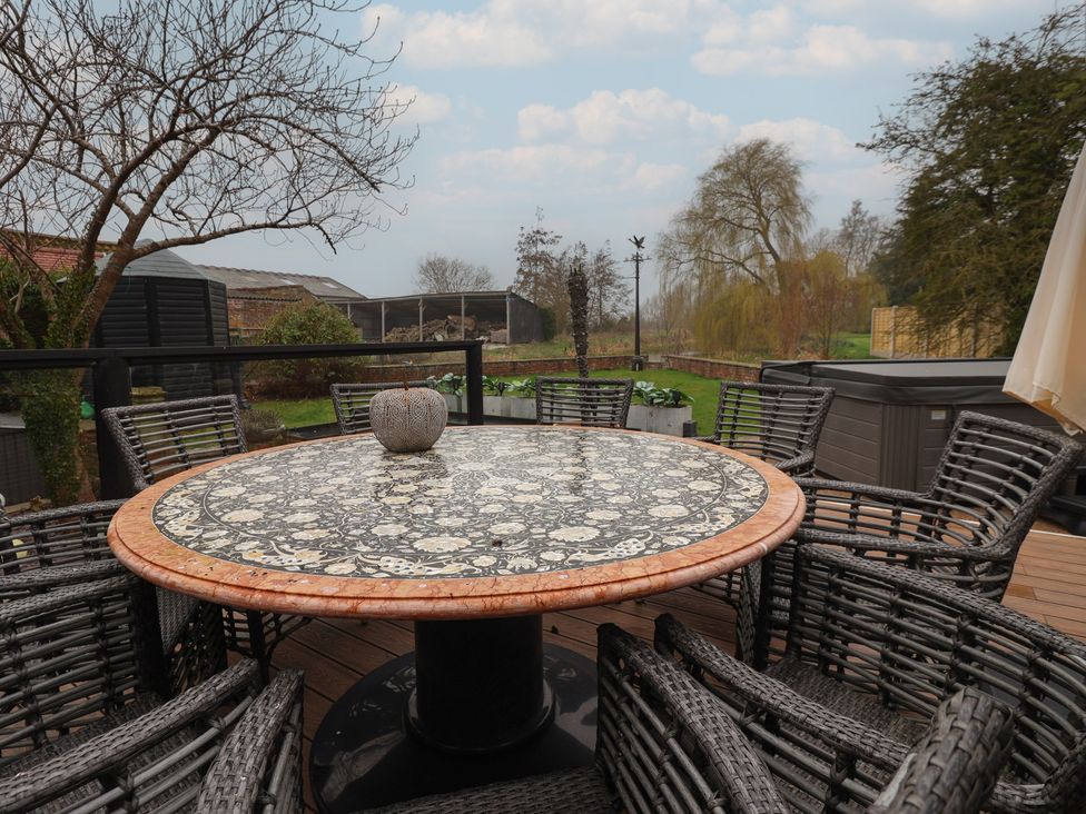 An outdoor dining area with a round table and chairs at Mill Race Cottage in Driffield