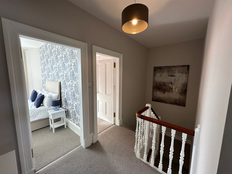 A hallway with a staircase and doorways to bedrooms at Abbotsford in Kelso