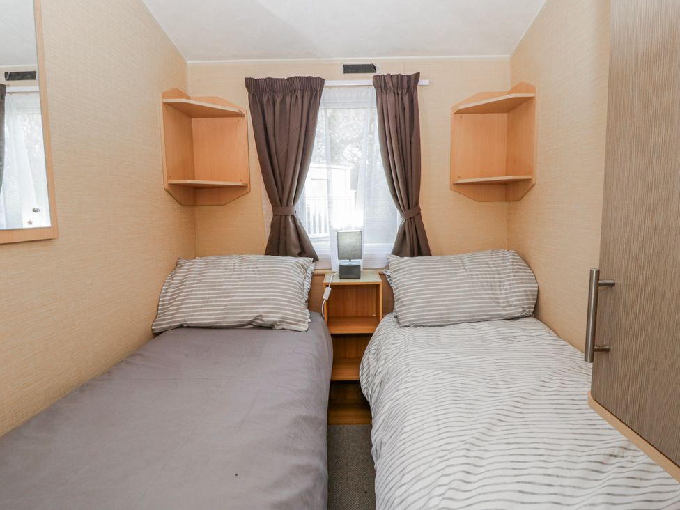 A bedroom with two beds and shelves at Ger Y Mor in New Quay