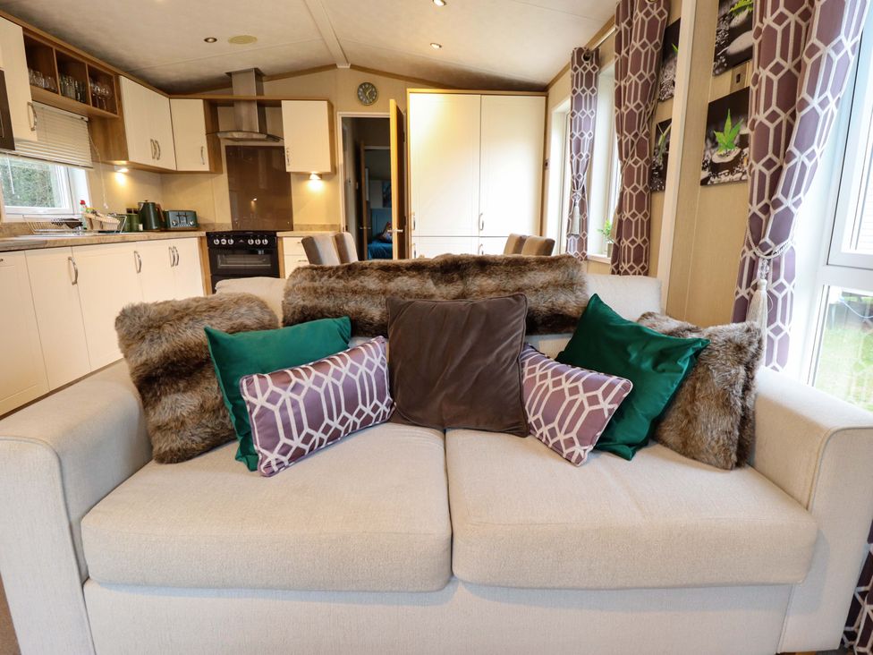 A living room with a couch and kitchen area at 108 Fox Burrow Hang, Great Yarmouth