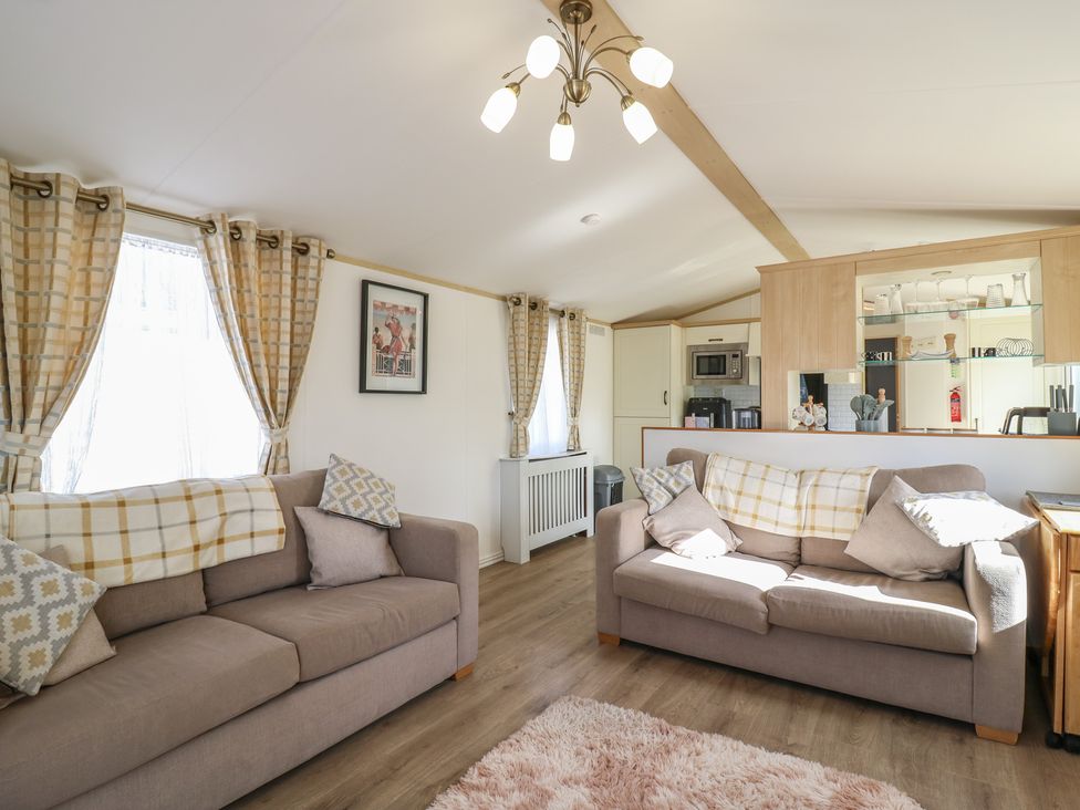 A living room with sofas and kitchen counter at 2 bed Caravan Stowmarket