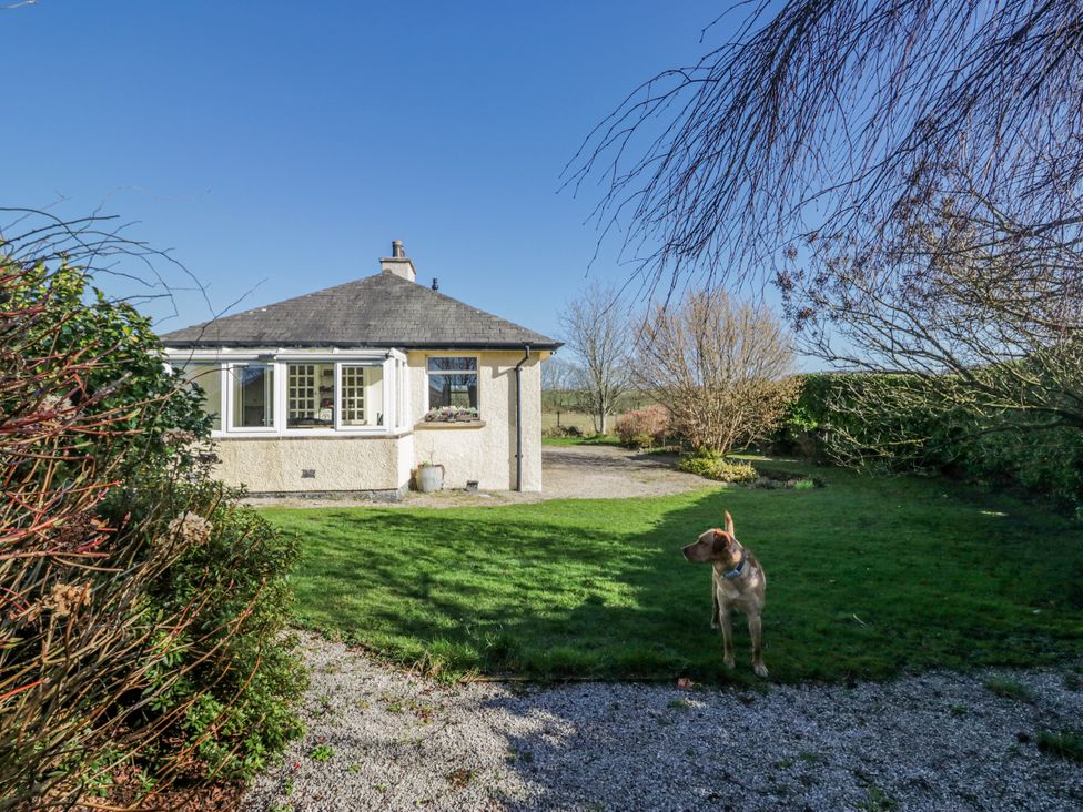 A house with a lawn and a dog in front at Linden Lea Grange-Over-Sands