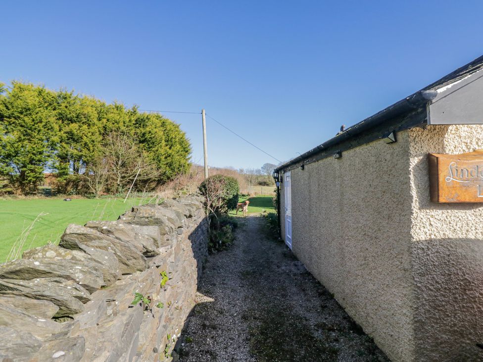 A pathway beside a stone wall with trees at Linden Lea in Grange-Over-Sands