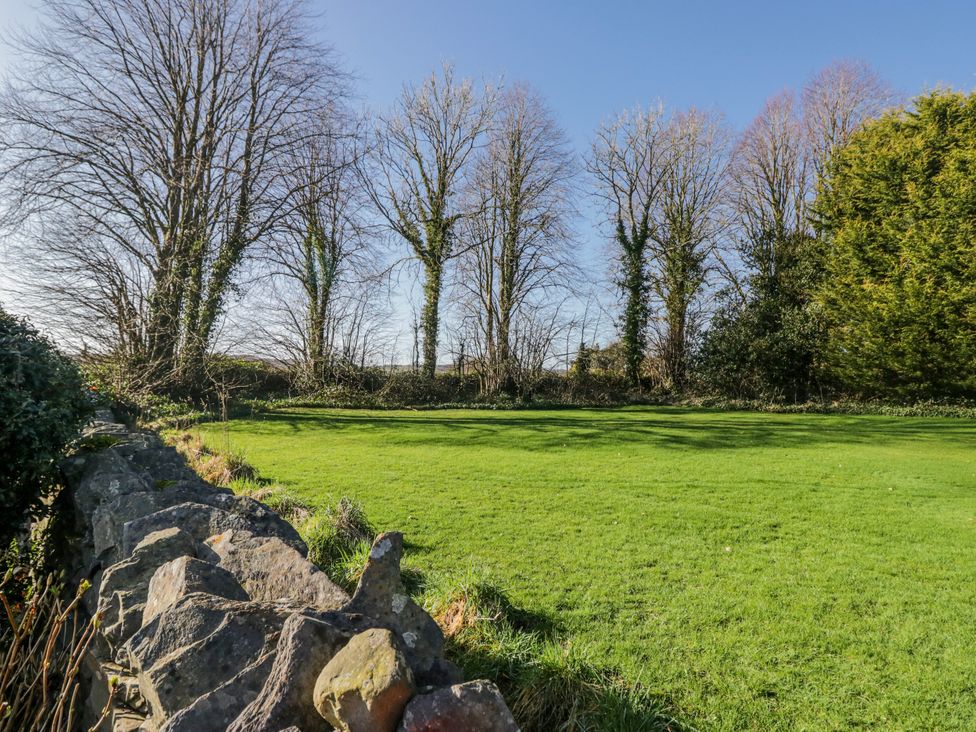 A garden with trees and a stone wall at Linden Lea in Grange-Over-Sands