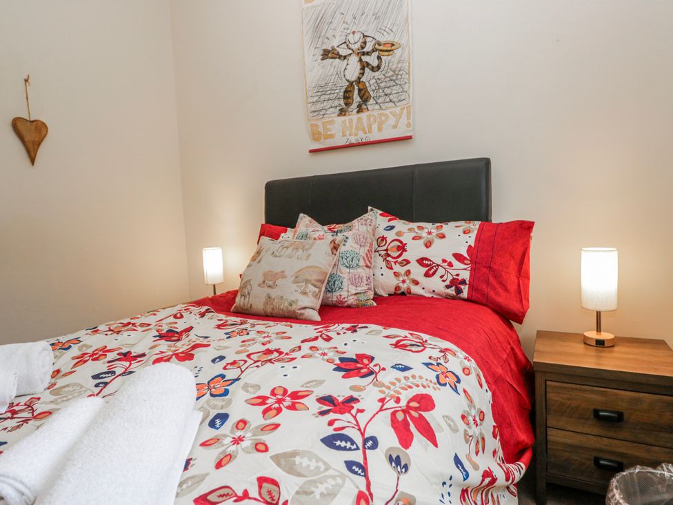 A bedroom with a bed, pillows, lamp and wall art at Linden Lea Field Broughton near Cartmel