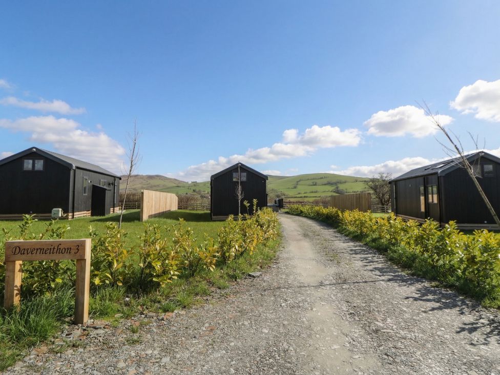 An outdoor view featuring cabins along a gravel path at Daverneithon 3 Near Llandrindod Wells