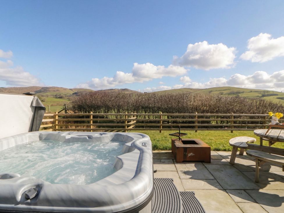 An outdoor area with a hot tub and a wooden table at Daverneithon 4 near Llandrindod Wells