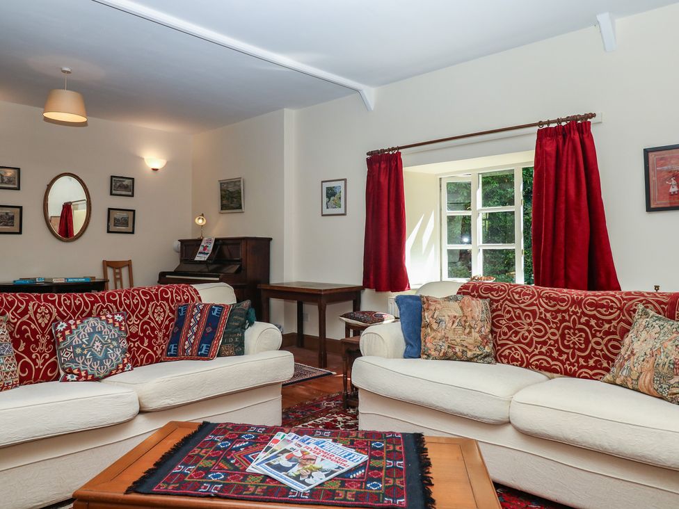 A living room with sofas and a piano at Lukesland Wing in Ivybridge