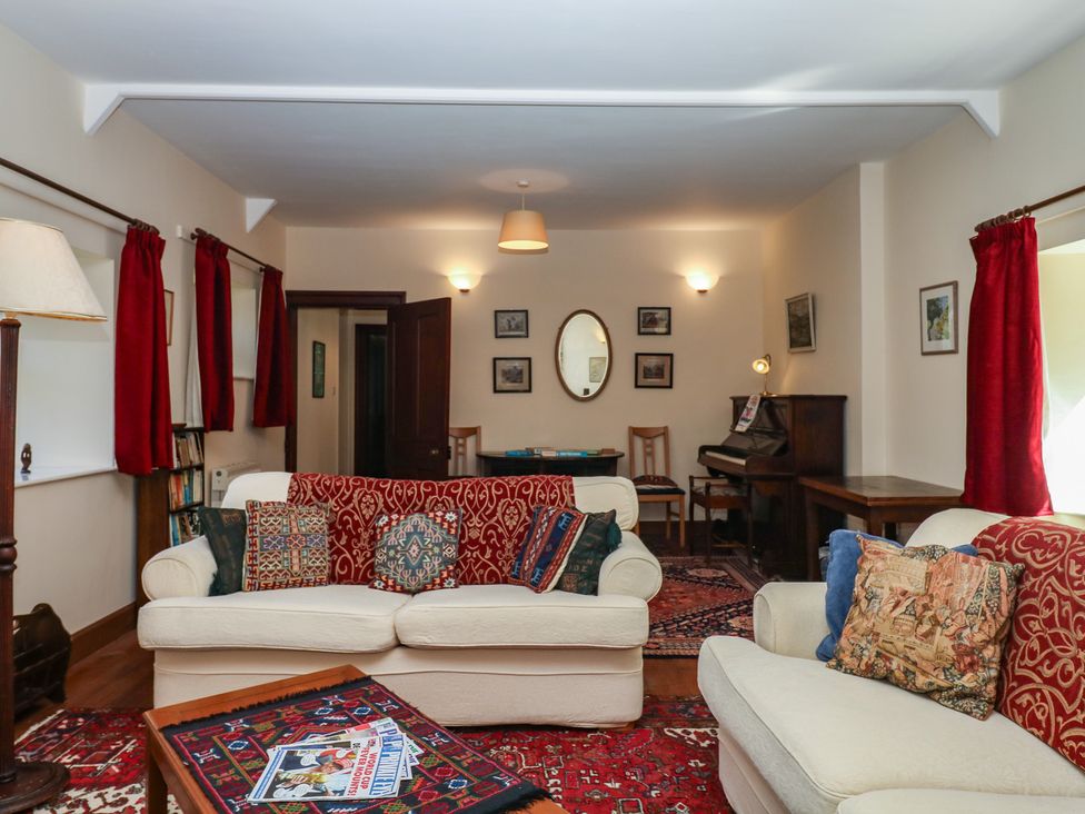 A living room with sofas and a piano at Lukesland Wing in Ivybridge